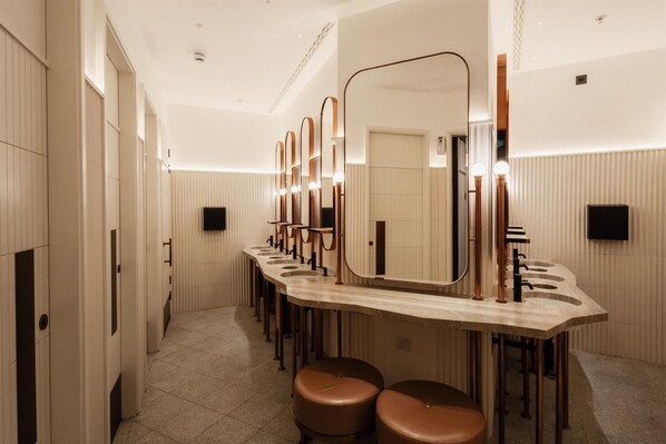 A modern bathroom with multiple sinks, mirrors, and stools.
