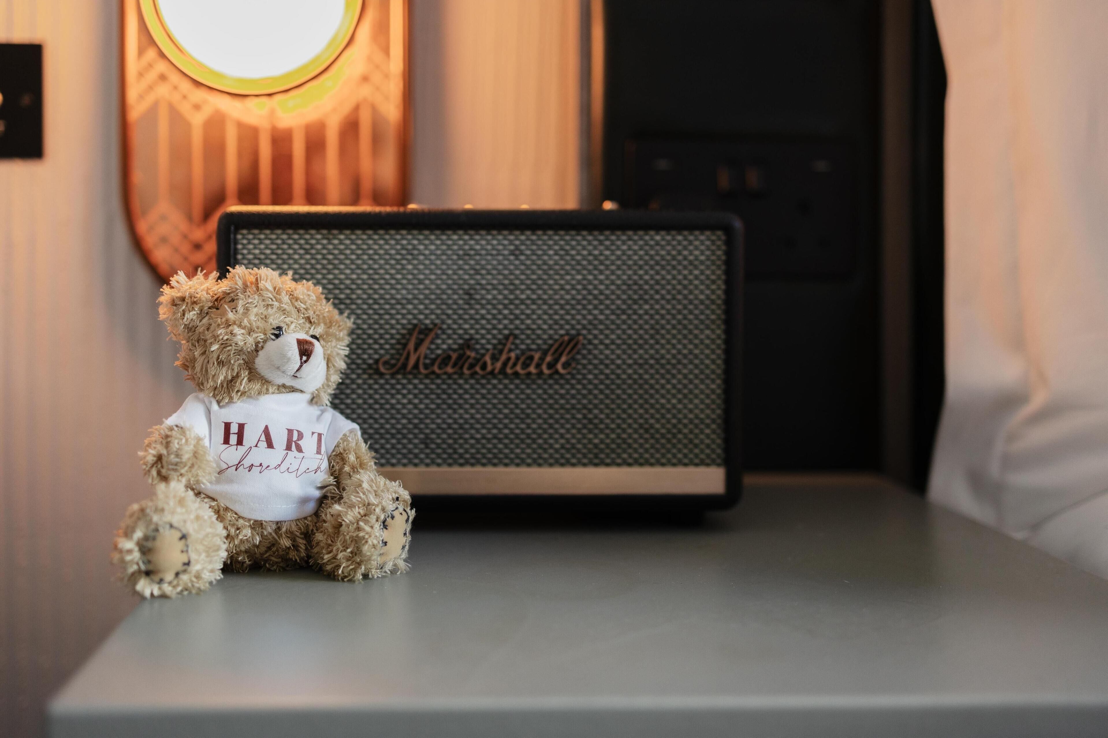 A teddy bear on a table with a Marshall speaker in the background.