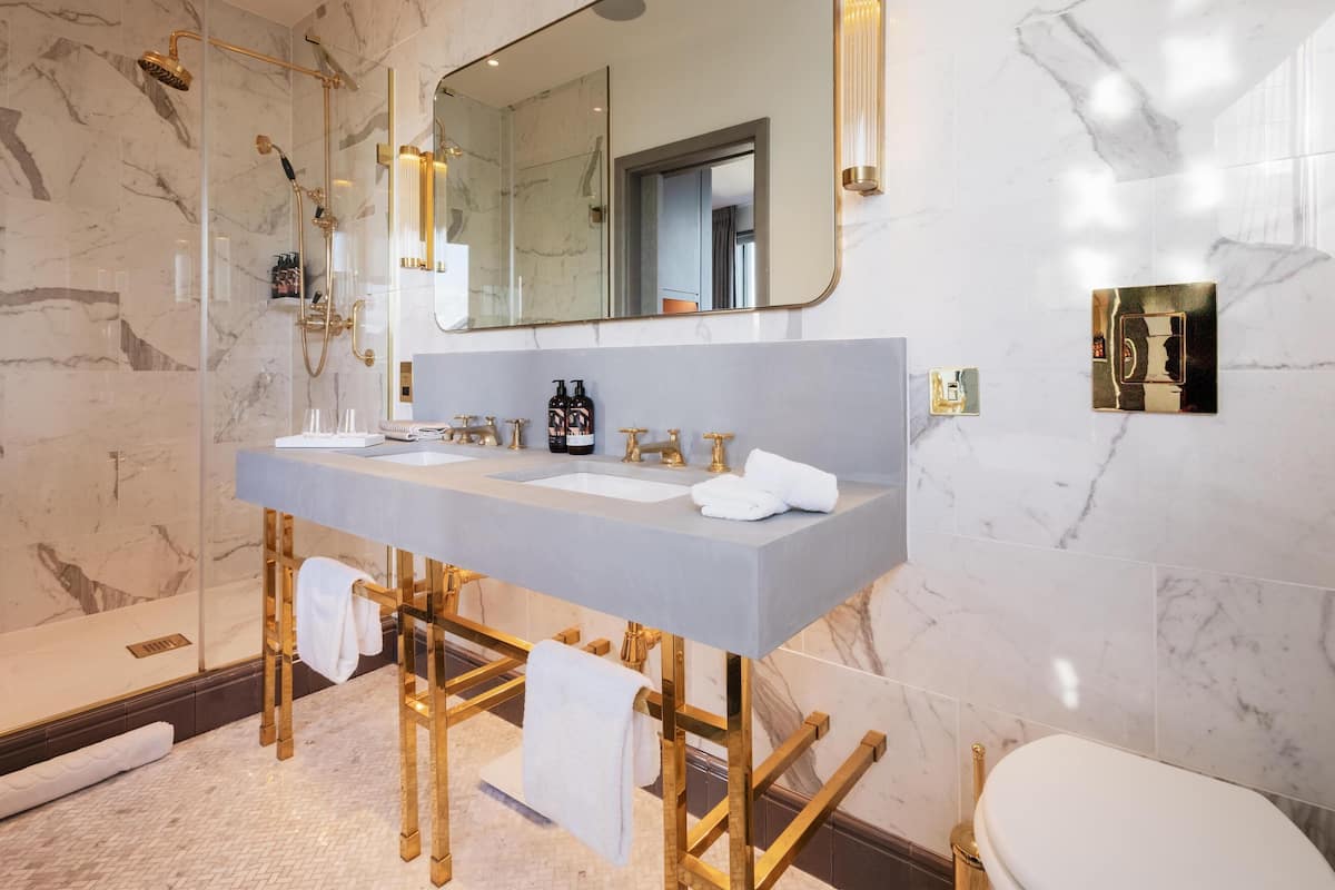 A modern bathroom with a marble shower, dual sinks, and a large mirror.