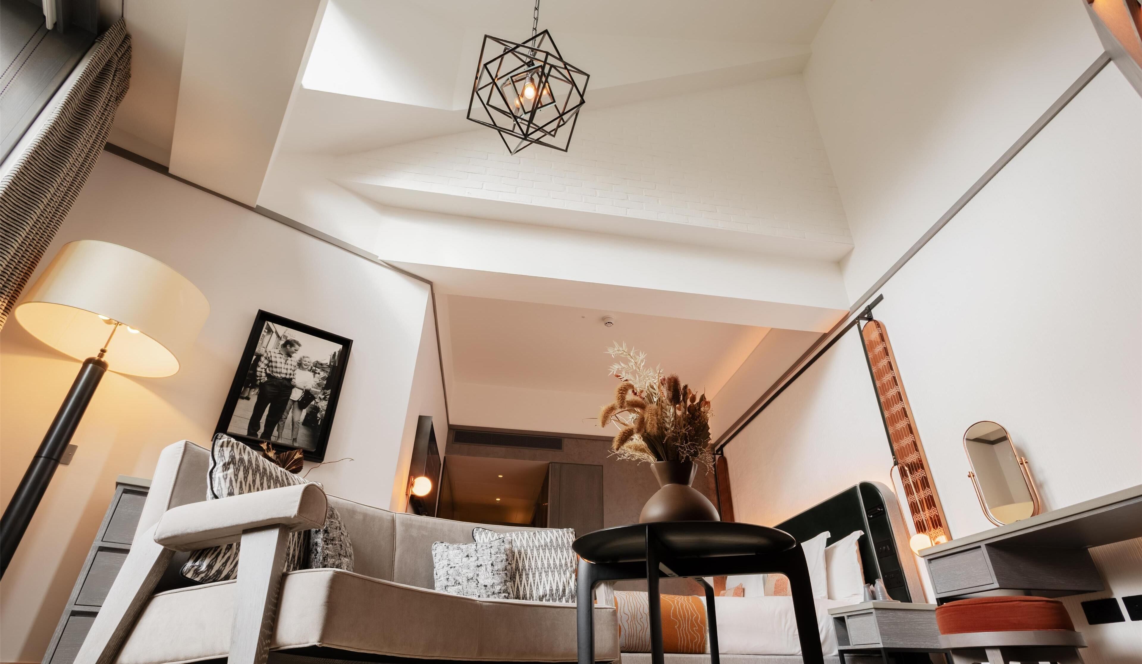 En moderne stue med sofa, spisebord, stol, hængende lampe og et indrammet fotografi på væggen.