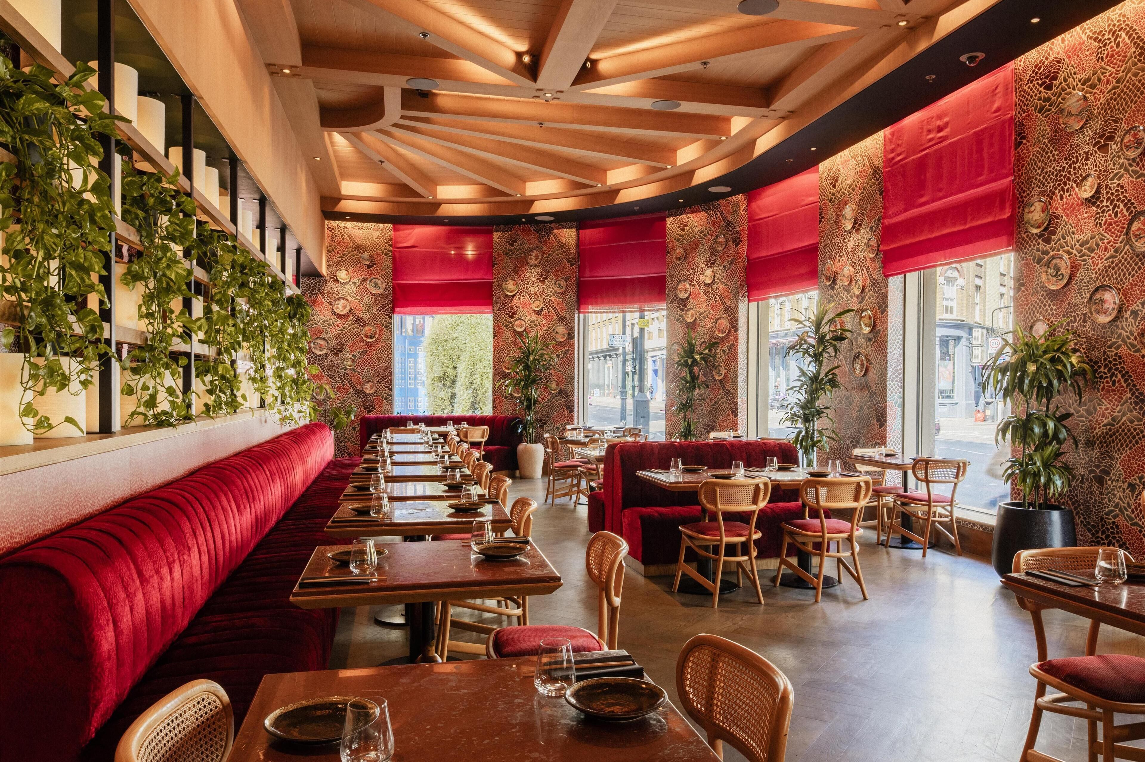 A restaurant with red upholstered booths, wooden tables, and chairs.