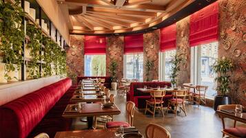 A restaurant with red upholstered booths, wooden tables, and chairs.