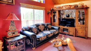 A living room with a black leather sofa, a glass coffee table, and a wooden cabinet with decorative items. - Scenic Wonders Christmas Cabin 3 Bedroom (Yosemite National Park)