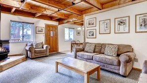 A cozy living room with a fireplace, a sofa, a coffee table, and framed artwork on the walls. - Scenic Wonders Clark Cabin 3 Bedrooms (Yosemite National Park)