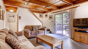 A cozy living room with a wooden ceiling, a sofa, a coffee table, and a TV. - Scenic Wonders Clark Cabin 3 Bedrooms (Yosemite National Park)