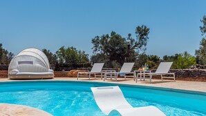Une piscine avec des chaises longues et un auvent.