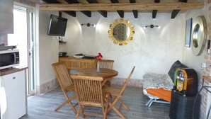 Une cuisine compacte équipée d’un four à micro-ondes, d’un petit réfrigérateur et d’un coin repas avec des chaises et une table en bois.