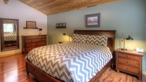 A bedroom with a wooden bed, a nightstand, a dresser, a mirror, and a framed picture on the wall. - Scenic Wonders Dogwood Manor 3 Bedrooms (Yosemite National Park)