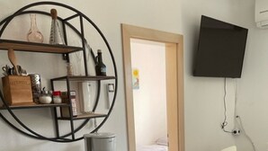 Eine kleine Küchenzeile mit einem blauen Kühlschrank, einer Kaffeemaschine und einem Regal mit Küchenutensilien.