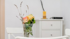 Ein weißer Tisch mit einer klaren Vase, gefüllt mit Blumen und Grünpflanzen.