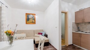Ein kompakter Wohnbereich mit Essbereich, einer Couch, einem Gemälde und einer Küchenzeile.