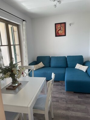 Un salon avec un canapé bleu, une table blanche et un tableau accroché au mur.