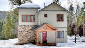A two-story building with a stone foundation and a red door.