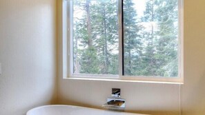 Un baño con ventana que da a un bosque.