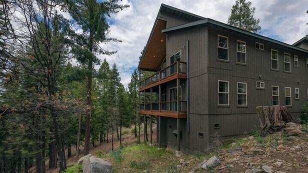 Un immeuble à plusieurs étages doté d’un balcon, entouré d’arbres.
