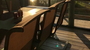 A wooden deck with a table and chairs, overlooking a body of water and trees. - Papa's Place - A secluded lake front property on the edge of Whitefish (Whitefish)