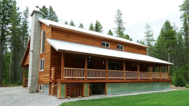 A log cabin with a covered porch, a stone chimney, and a gravel driveway. - Papa's Place - A secluded lake front property on the edge of Whitefish (Whitefish)