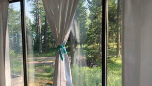 A room with large windows, white curtains tied with a green ribbon, and a wooden sign above the windows. - Papa's Place - A secluded lake front property on the edge of Whitefish (Whitefish)