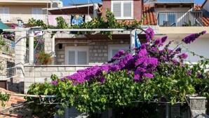 Un edifici residencial amb parets de pedra, teulada vermella i un balcó amb barana metàl·lica.
