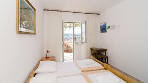 Habitació amb dos llits, una taula petita, una cadira i una finestra amb vista a la ciutat.