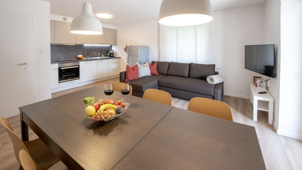 Un apartamento moderno con comedor, cocina, sala de estar y televisor.