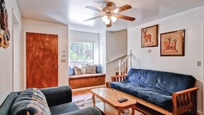 A living room with a blue sofa, a wooden coffee table, and a ceiling fan. - Scenic Wonder Pinetree Retreat 3 Bedroom (Yosemite National Park)