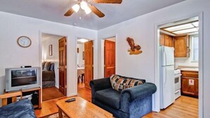 A compact living space with a sofa, a television, a wooden table, and a ceiling fan. - Scenic Wonder Pinetree Retreat 3 Bedroom (Yosemite National Park)