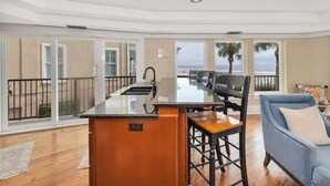 A modern kitchen with a large island, a dining area with a view of the ocean, and a cozy seating area. - First Floor, Oceanfront Condo, Concierge Service! (Saint Simons Island)