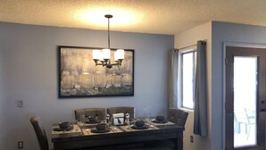 A dining area with a dark wooden table set for four, a chandelier, and a large abstract painting on the wall. - Cntrl Tucson Home, Salt Water Pool, Hot Tub, Bike Path, 3mi to UofA TPT 20128463 (Tucson)