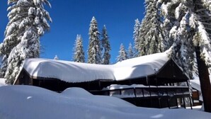 A snow-covered lodge with a roof and a wooden structure in the foreground. - Scenic Wonders Quail Crossing 3 Bedrooms (Yosemite National Park)