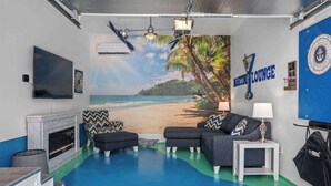 A room with a beach mural, a fireplace, a sofa, and a TV.
