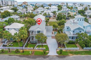A residential area with a house marked by a red pin, surrounded by palm trees and a white picket fence.