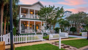A two-story house with a white picket fence, a front porch, and a balcony.