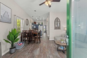 A spacious living area with a dining table, chairs, a sofa, and a potted plant.