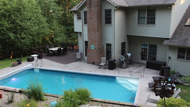 A backyard with a swimming pool, patio furniture, and a brick chimney.