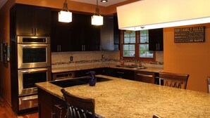 A modern kitchen with stainless steel appliances, granite countertops, and a large island with bar stools.