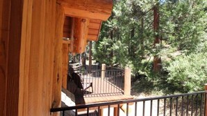 A wooden cabin with a balcony overlooking a forested area.