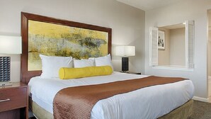 Una habitación de hotel con una cama grande, dos mesitas de noche, una lámpara de noche, un cuadro en la pared y una ventana con contraventanas.