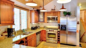 Una cocina con armarios de madera, electrodomésticos de acero inoxidable e iluminación colgante.