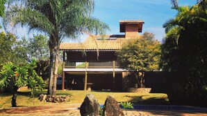 A traditional building with a tiled roof, surrounded by lush greenery and a clear blue sky. - CHÁCARA MARANATA - ATIBAIA | Rentals for Weekends, Holidays and Seasons. (ATIBAIA)