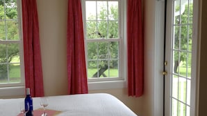 A bedroom with a bed, a window with curtains, and a door leading outside. - Mallard Cottage - Pet friendly (Newfield)