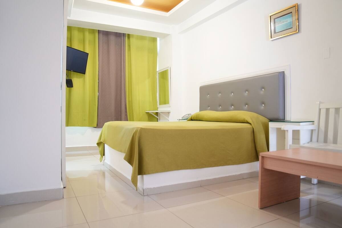 Une chambre à coucher comprenant un lit, une table de chevet et un bureau avec une chaise.
