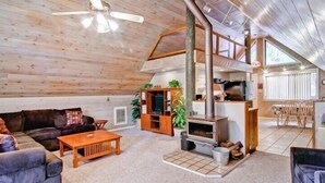 A cozy log cabin interior with a wooden ceiling, a fireplace, a sofa, a coffee table, and a dining area. - Scenic Wonders Yosemite Escape 3 Bedroom (Yosemite National Park)