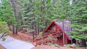 A cabin with a red exterior, a balcony, and a wooden deck. - Scenic Wonders Yosemite Escape 3 Bedroom (Yosemite National Park)