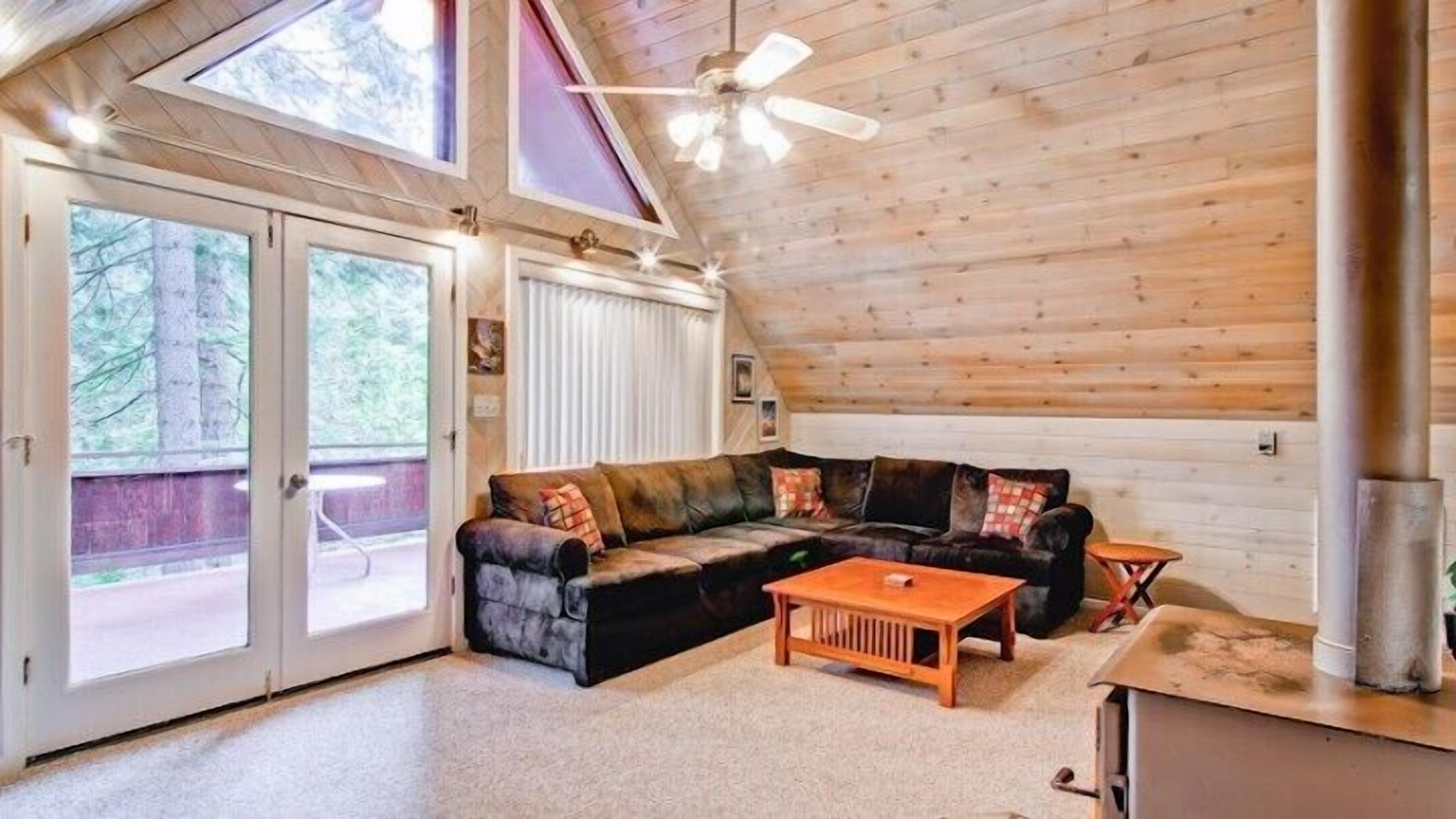 A cozy living room with a sectional sofa, a wooden coffee table, and a ceiling fan.