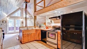 A modern kitchen with wooden cabinets, a stainless steel refrigerator, and a large window providing natural light. - Scenic Wonders Yosemite Escape 3 Bedroom (Yosemite National Park)