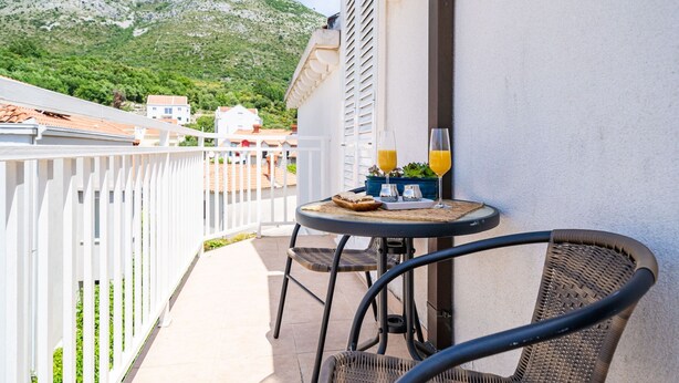 Un balcon avec une table, deux chaises et une vue sur une montagne.