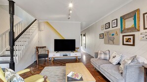 A living room with a TV, sofa, and a staircase. - Lauren's Place - This property is the perfect base for exploring all the region has to offer! (BRIGHT)