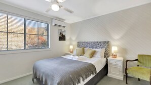 A bedroom with a bed, bedside tables, a chair, a ceiling fan, and a window with blinds. - Lauren's Place - This property is the perfect base for exploring all the region has to offer! (BRIGHT)