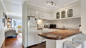 A modern kitchen with white cabinetry, a wooden countertop, and a built-in oven. - Lauren's Place - This property is the perfect base for exploring all the region has to offer! (BRIGHT)